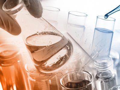 Lab glassware with liquids and a pipette in a scientific setting.