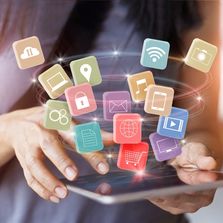 Women holding a tablet with floating social channels and media icons.