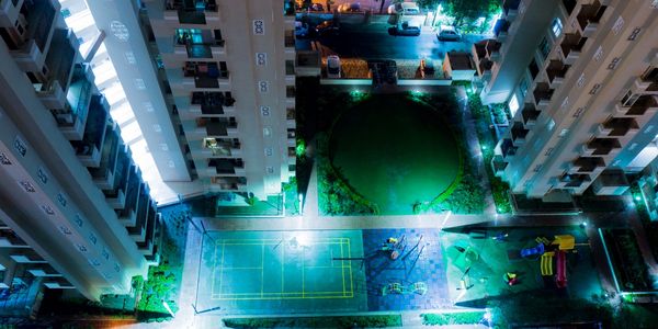 Aerial night view of a residential complex with illuminated playground and green area.