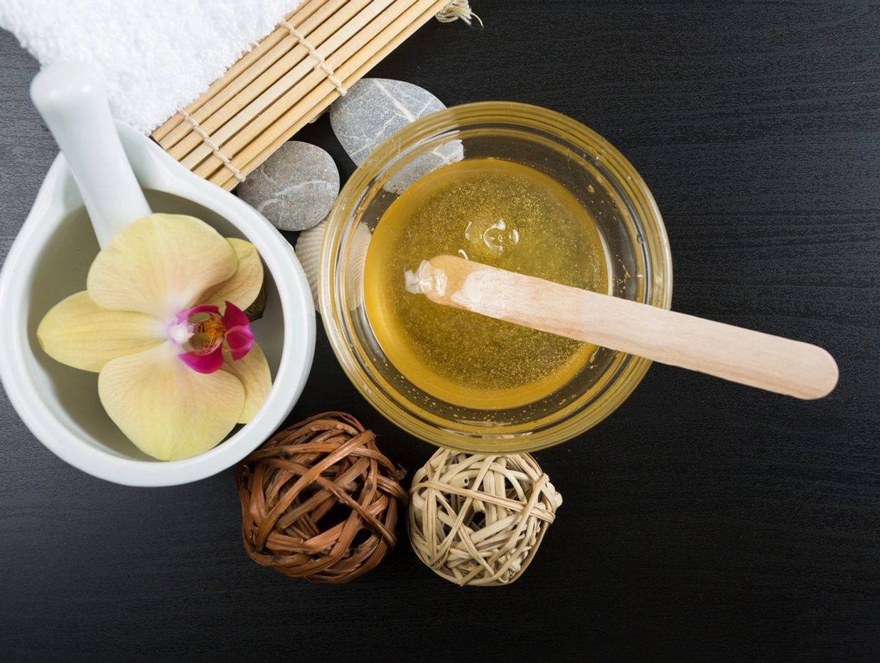 Spa ingredients including honey, orchid, stones, and bamboo on black surface.