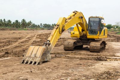 Yellow excavator working on a construction site with cleared land.