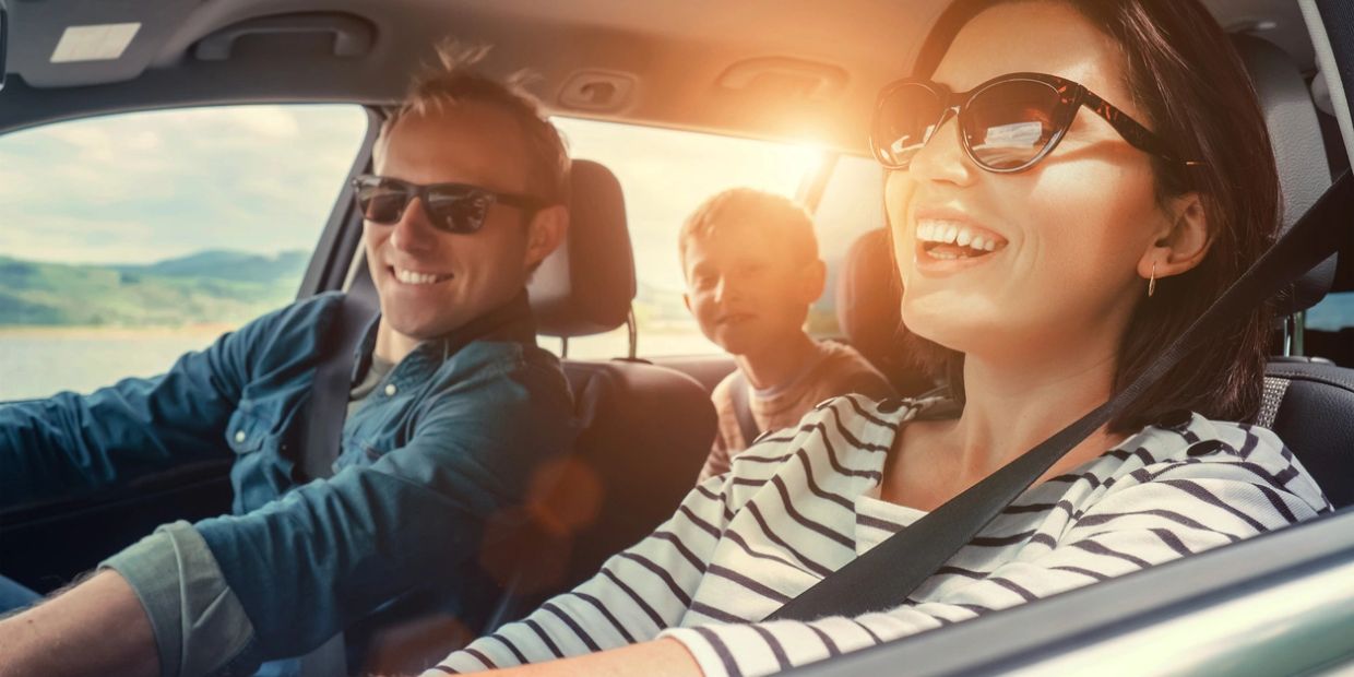 Happy family enjoying a sunny car ride together.