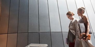 Two women walking outdoors with shopping bags.
