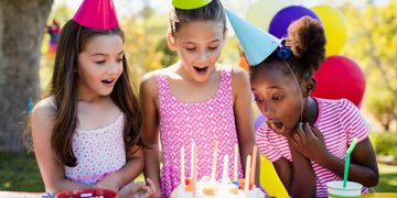 three girls standing around birthday cake decoration