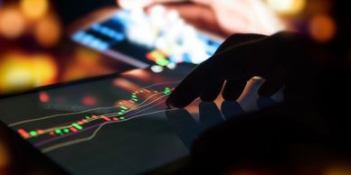 hands touching tablets with candle charts visible and trend lines