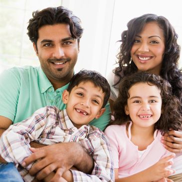 Happy family of four smiling together indoors.
