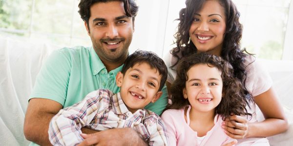 A happy family of four smiling together indoors.