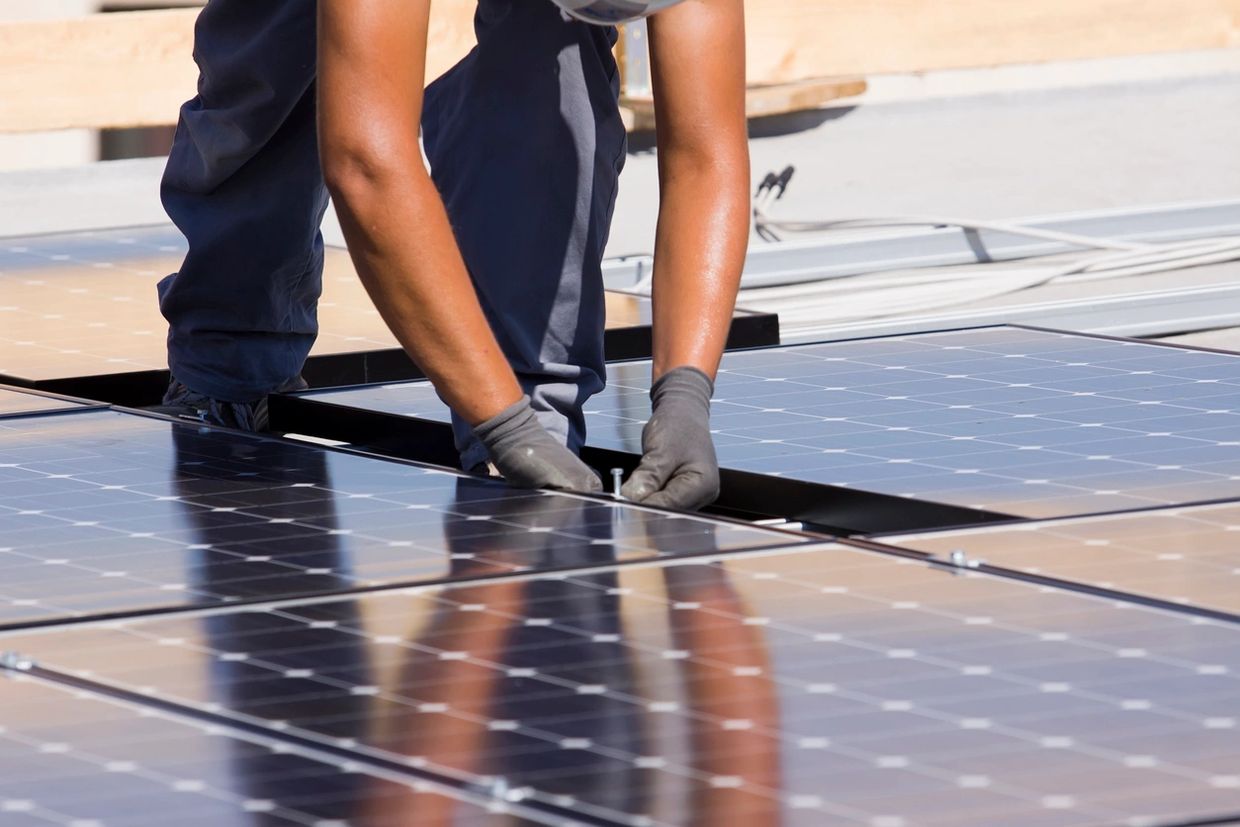 An installer installing solar panels to meet BASIX requirements