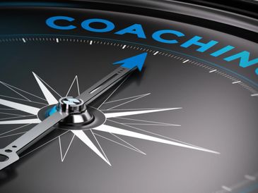 A compass needle pointing towards the word 'COACHING' in blue.