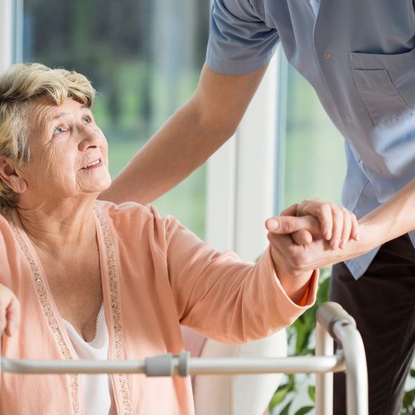 female senior getting assistance from a caregiver to stand up