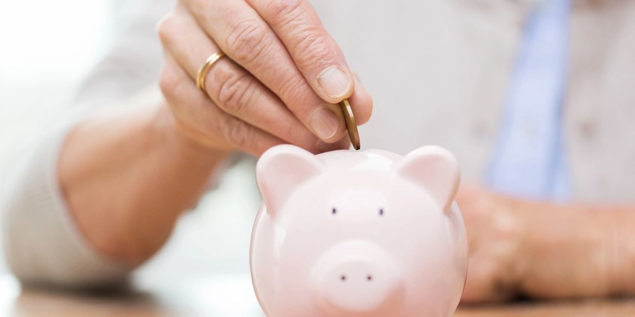 a person putting a coin in a piggy bank.