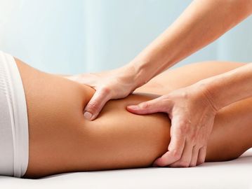 Therapist giving a deep tissue massage on a person's thigh.