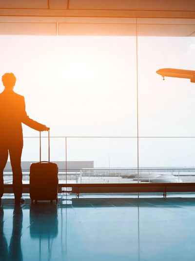 Silhouette of a traveler at the airport with luggage watching a plane.
