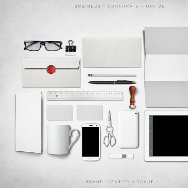 Flat lay of white and black business stationery and tech items on a light background.