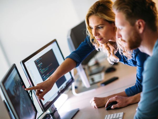 Two people working on coding at a computer.
