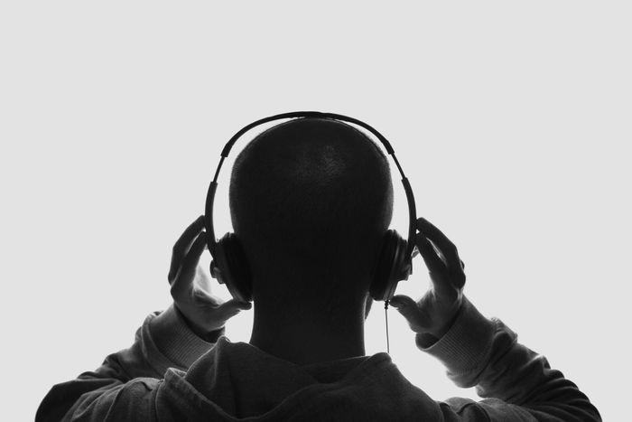 Person wearing headphones, viewed from behind against a plain background.