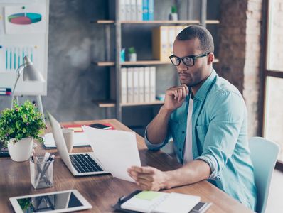 Man working remotely from home at his desk with laptop and documents