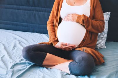 mother on bed holding belly