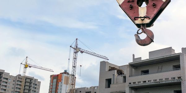 Construction cranes and buildings under development against a cloudy sky.