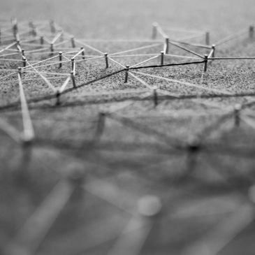 Close-up of interconnected pins and strings forming a network on a board.