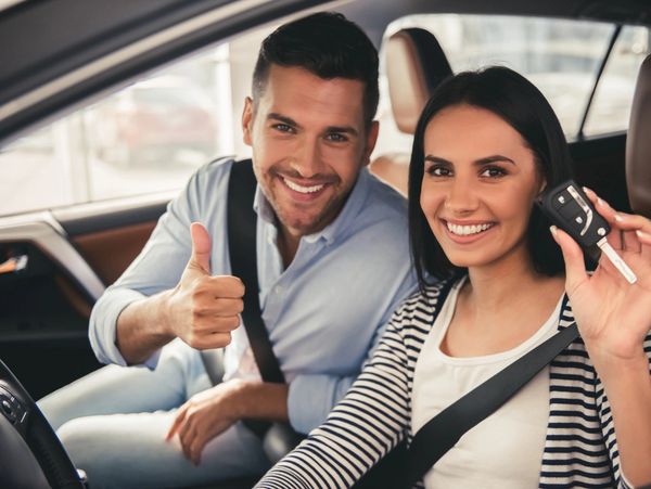 Smiling couple holding car keys.