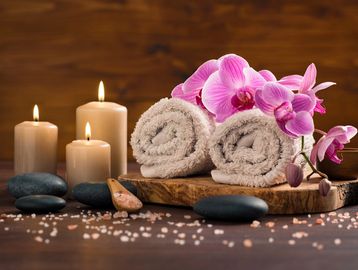 3 candles next to 2 towels decorated with stones