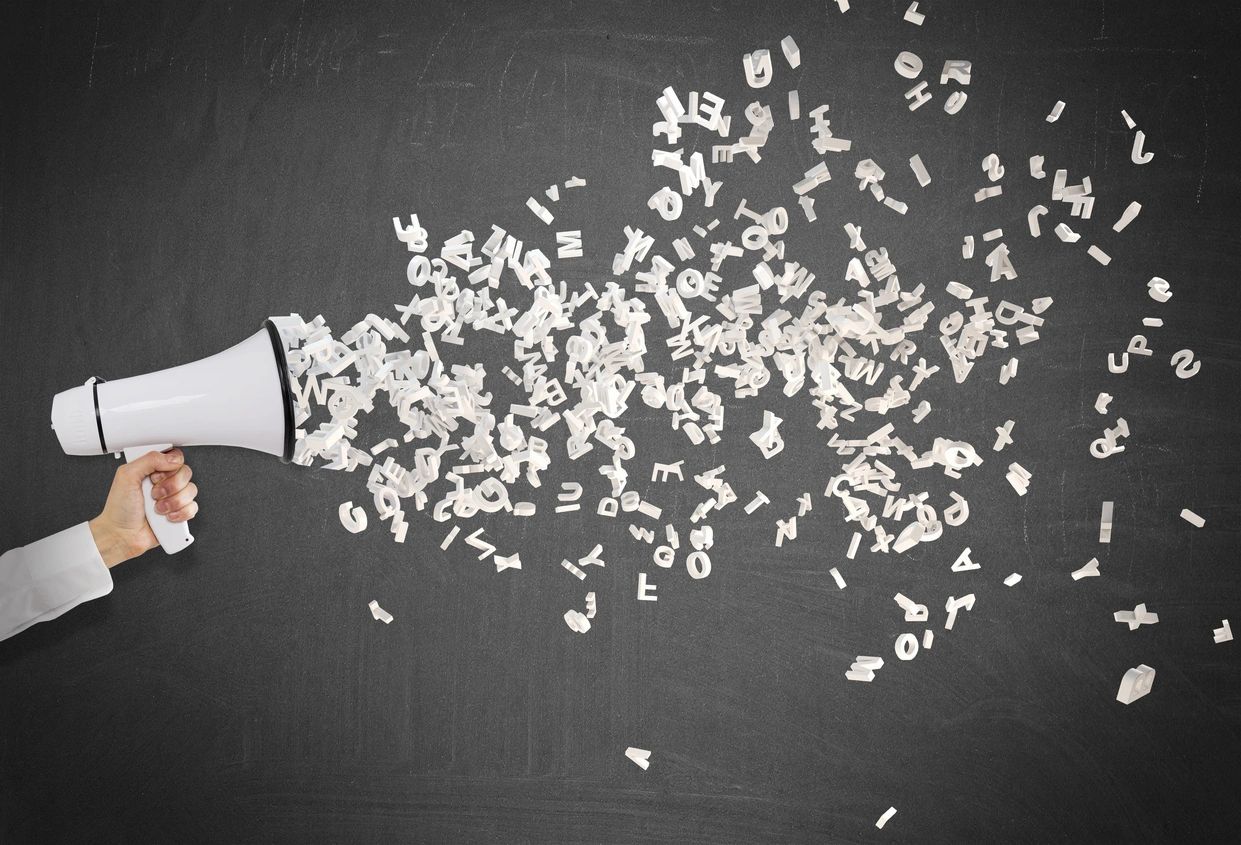 Stock  photo, showing letters streaming out of a handheld loudspeaker as if visualizing sound .