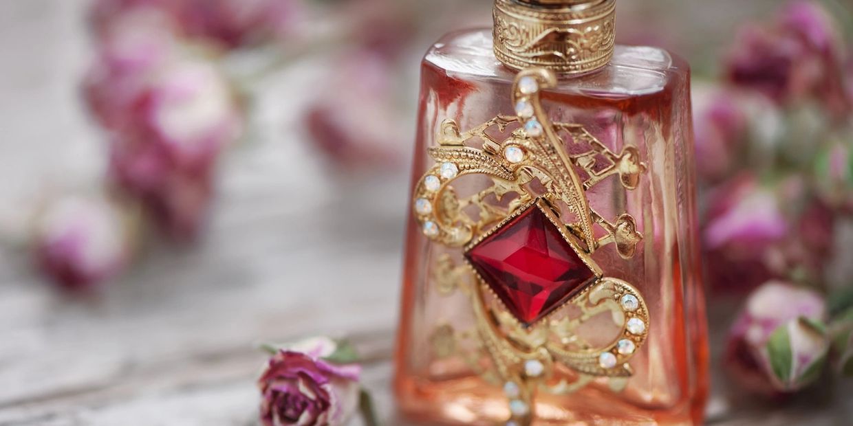 Perfume bottle on table with pink roses.