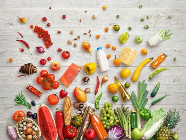 a colorful assortment of fruits and veggies on a white wooden background