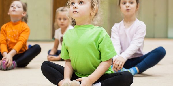 Close up shot of some small children doing yoga inside a room