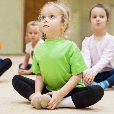 Children doing seated stretches indoors.