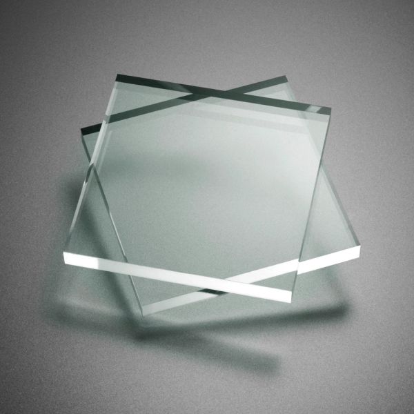 Three overlapping transparent glass squares on a gray surface.