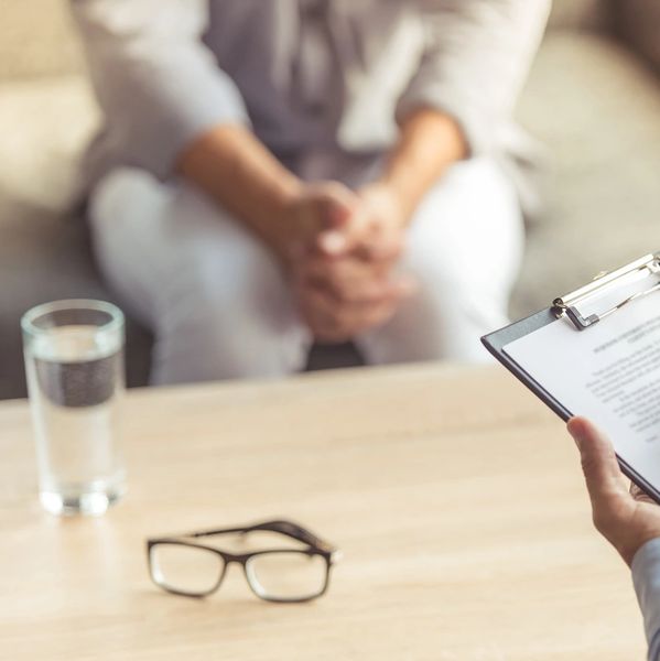 Person in therapy session with counselor taking notes.