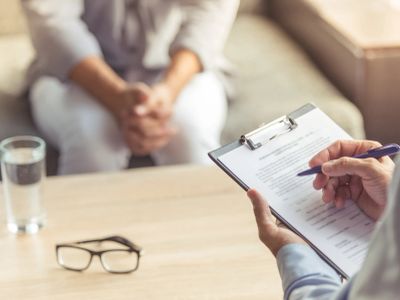 Patient consulting a professional with a clipboard and questionnaire.