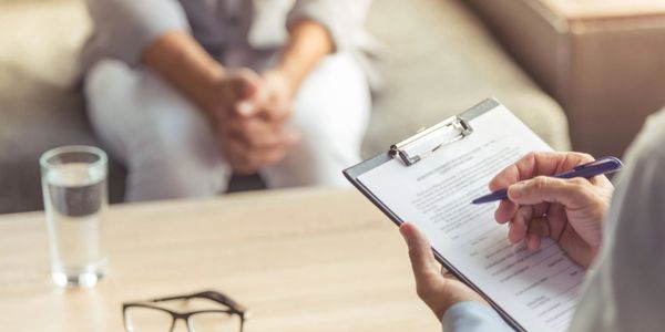 therapist writing on clipboard with client sitting on a couch