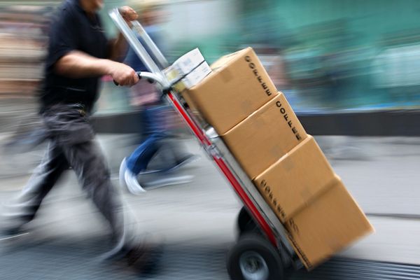 Blurred motion of a worker transporting coffee boxes on a hand truck.