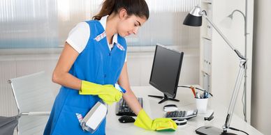 Woman cleaning white desk surface. 