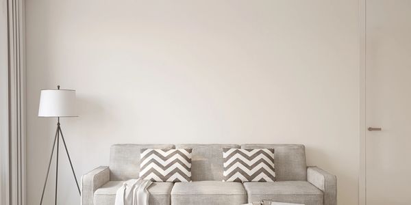 Minimalist living room with gray sofa, chevron pillows, and modern floor lamp.
