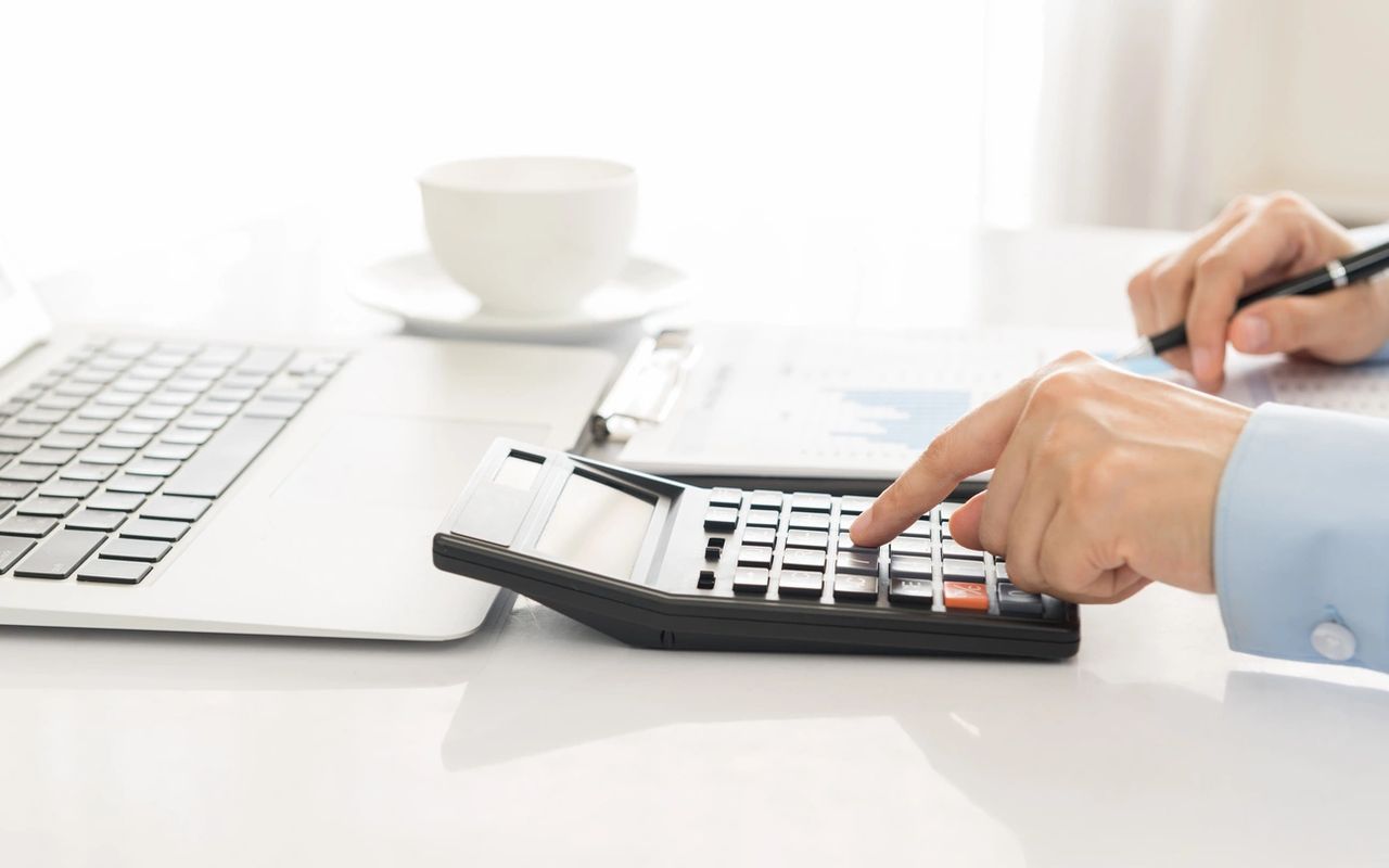 A calculator being used while reviewing a report at his desk.