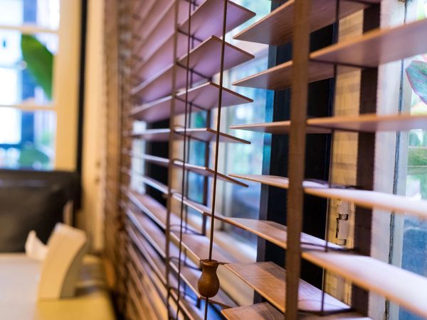 Close-up of wooden blinds on a window with a cozy indoor setting.