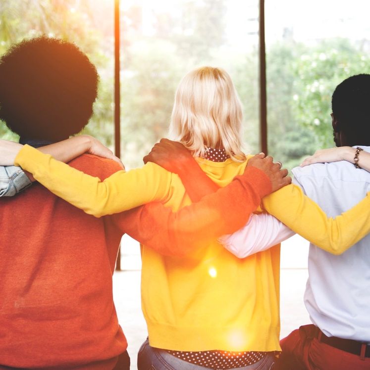 Group of diverse friends with arms around each other, symbolizing unity and support.