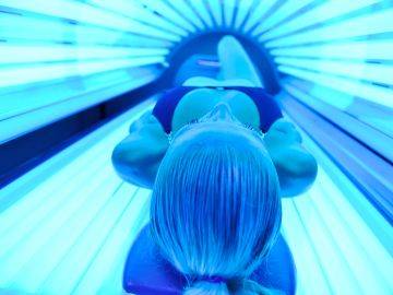 Person tanning in a bright blue tanning bed.