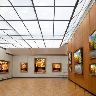 Modern art gallery with framed paintings and large skylight ceiling.