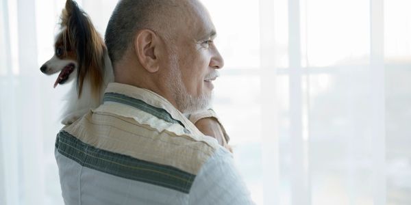 Older gentleman holding his dog and enjoying his company. 