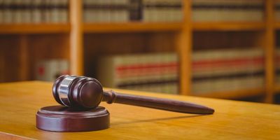 Wooden judge's gavel on a desk with law books in the background.