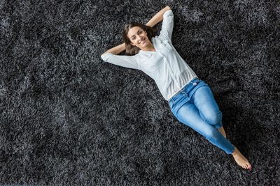 Woman laying on her brand new cleaned area rug with a smile on her face