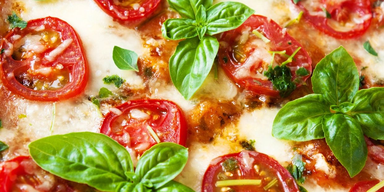 Close-up of a Margherita pizza with fresh basil and tomatoes.