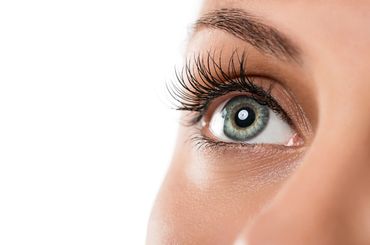 Close-up of a green eye with long eyelashes.