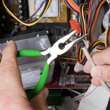 Hands using pliers and a probe to test computer wiring inside a PC.