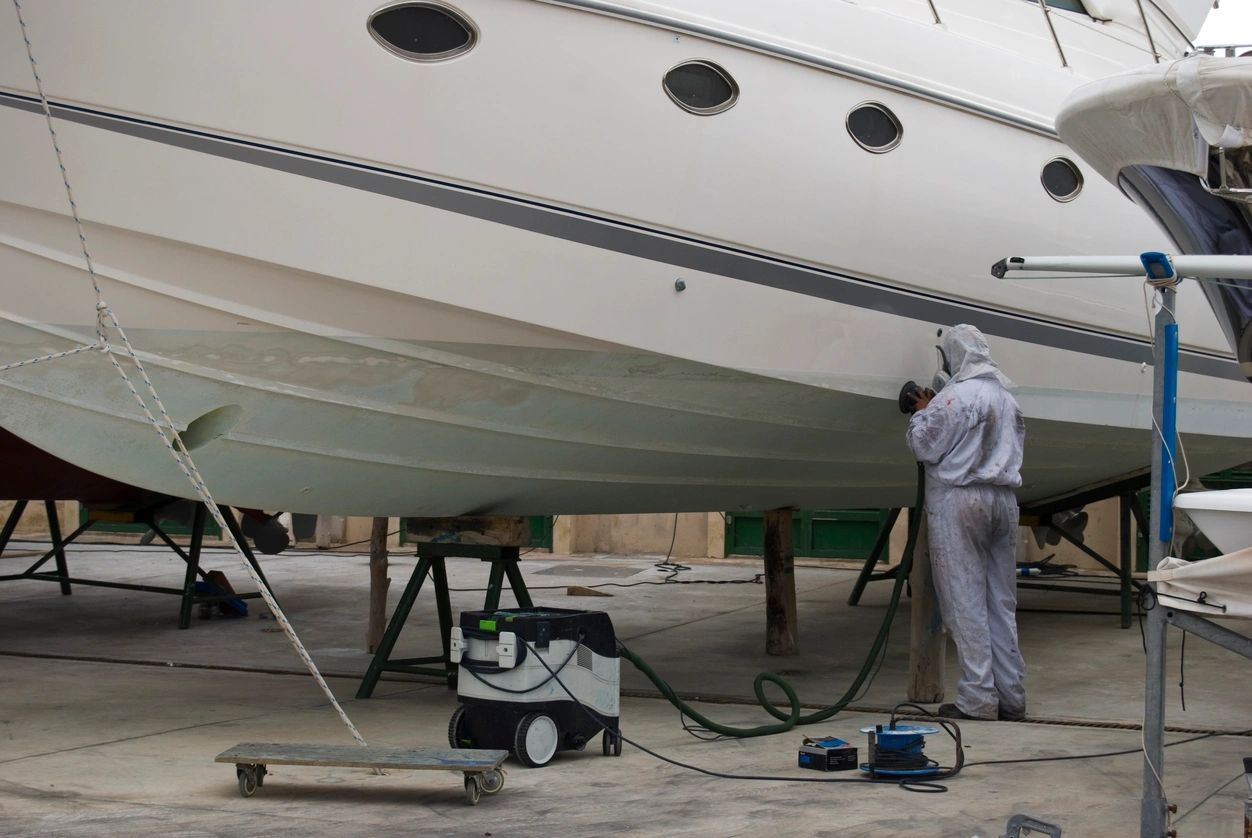 Contractor doing boat repair to a yacht on shore